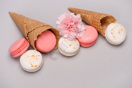 一组粉红色和白色马卡龙在华夫饼锥与康乃馨花马卡龙背景概念图片