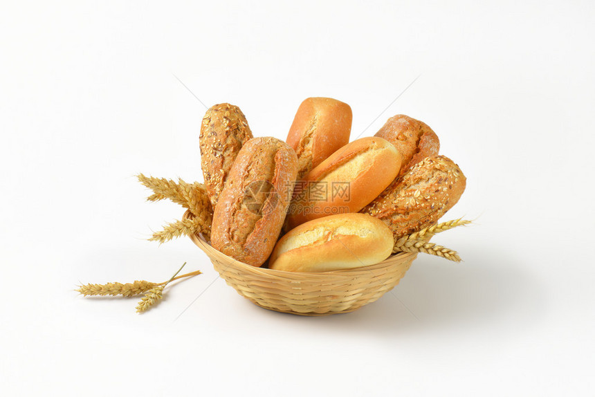 白色背景上一篮子各种面包卷和小圆面包图片