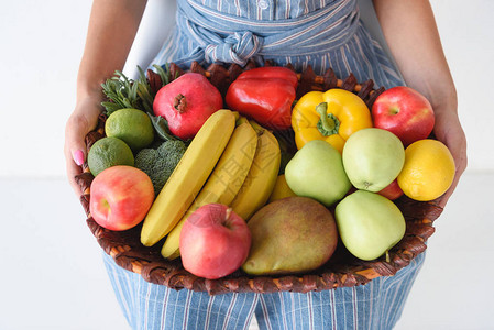 妇女拿着新鲜蔬菜和水果的篮子手握新图片
