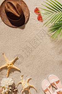 沙滩上带太阳镜和凉鞋的时尚草帽的顶视图图片