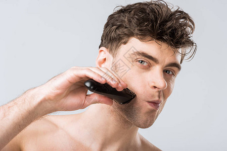 帅的男子用电动剃须刀刮胡子在图片