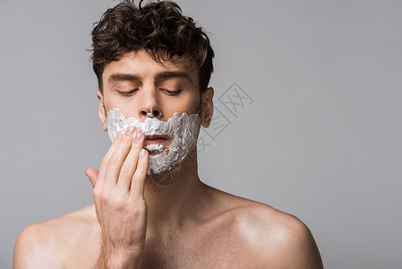 英俊的男人在脸上涂抹剃须泡沫背景图片
