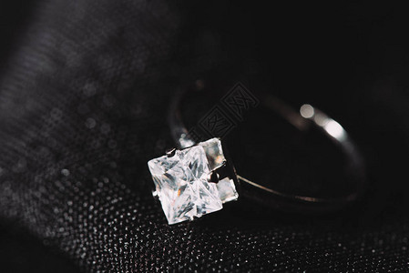 黑布上镶有纯正闪亮钻石的订婚戒指背景图片