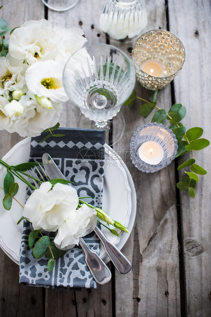 表设置与白花蜡烛和旧复古仿木桌上的眼镜复古夏季婚礼餐桌图片