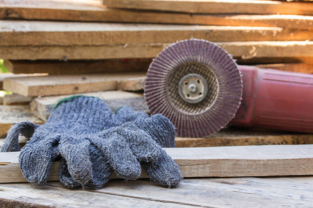 木制桌上的手套和电动砂纸工具后图片