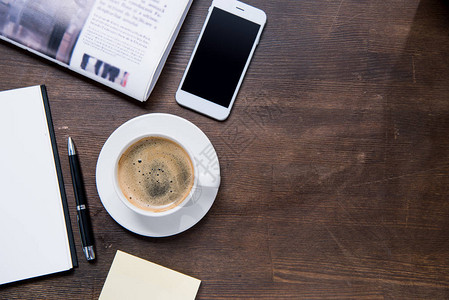 咖啡杯的顶端视图带空白屏幕的智能手机笔记本和木图片