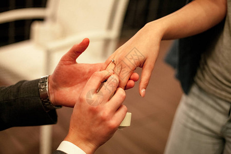 男人提出女婚姻求婚并用钻石订婚戒指在她的手指图片