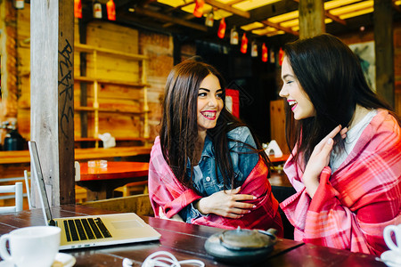 两个年轻漂亮的女孩坐在桌旁在网上找东西背景图片