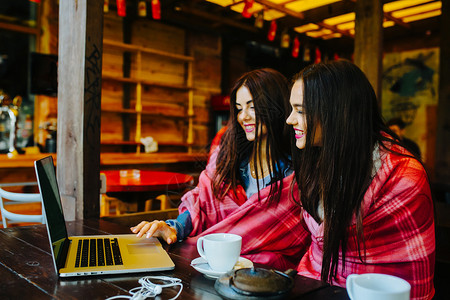 两个年轻漂亮的女孩坐在桌旁在网上找东西背景图片