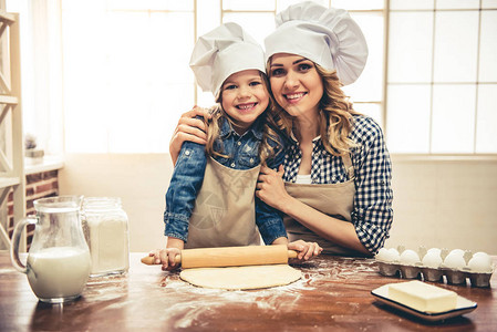 可爱的小女孩和她漂亮的妈穿着围裙和厨师帽图片