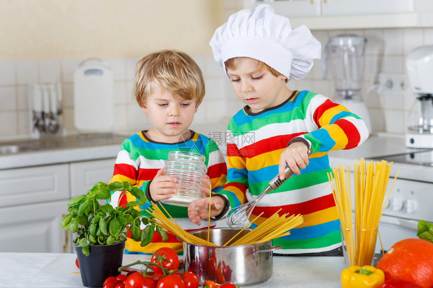 两个可爱的小兄弟在厨房里用意大利菜和新鲜蔬菜做意大利面条饭图片