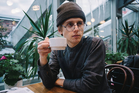 英俊的年轻学生带着眼镜男在咖啡馆喝咖图片