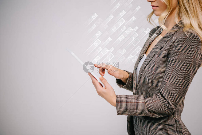 以发送孤立在灰色上的电子邮件图标的方式传送数字平板电脑的女商图片