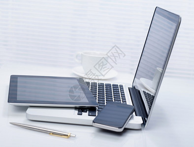 办公桌台的膝上型移动电话和平板电脑图片