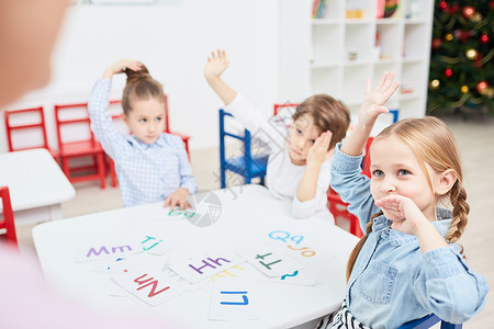 与教师一起学习字母表边用餐桌边举手图片