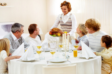大家族的肖像坐在节庆桌边看着吃美味火鸡盘图片