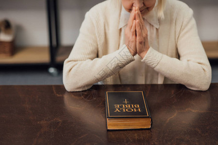 在家中的圣经面前坐着祷告的高龄妇图片