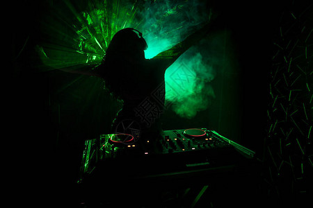 DJ之手调整dj甲板上的各种轨道控制频闪灯和雾背景图片