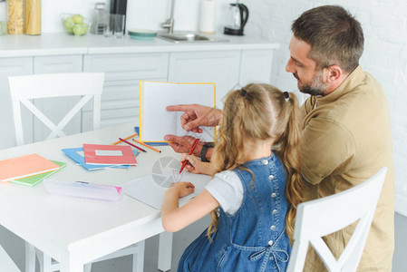 父亲和女儿在家厨房做家庭作业时图片