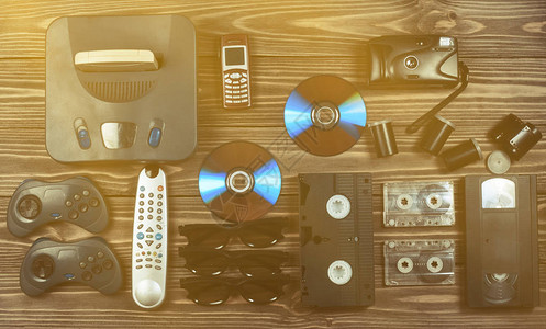 胶卷播放器老式媒体和信息技术娱乐90年代游戏机游戏手柄磁盘录音带录像带电话木桌上的胶卷相机背景