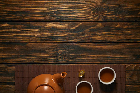 棕色陶瓷茶壶和竹垫上茶杯的风景图片