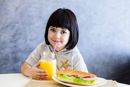 女孩在家吃早餐和喝橙汁的黑图片