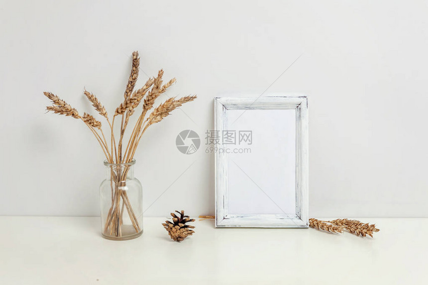 垂直框架样机与野生黑麦花束在靠近白墙的玻璃花瓶用于演示设计的空框架模型现代艺术的模板框架Hygge斯堪的纳维亚风格自然图片