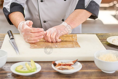 男厨用竹垫做日本寿司卷图片