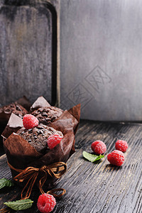 巧克力松饼在黑色纸质木制的老桌子上空背景图片