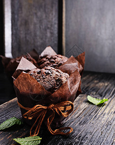 巧克力松饼在黑色纸质木制的老桌子上空背景图片