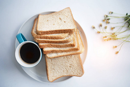 蓝色陶瓷咖啡杯黑咖啡加着切片面包在白桌边周图片