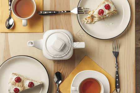 茶壶的顶视图两杯热茶和盘子上的美味蛋糕图片