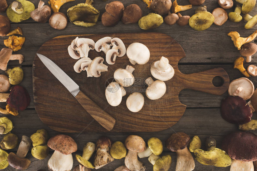 带刀和切蘑菇的木制切菜板的顶部视图图片
