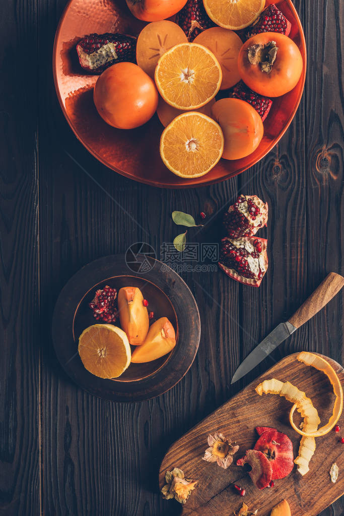 盘子上的橙子和石榴柿子的高视图图片