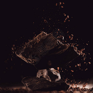 黑色背景中巧克力碎落在排列好的巧克力块图片