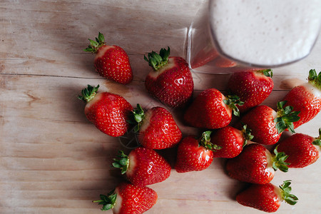 草莓冰沙奶昔与新鲜草莓在夏季木桌图片