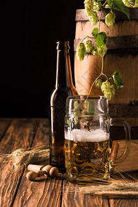 啤酒瓶一杯含泡沫泡小麦和木桶的新鲜啤酒图片