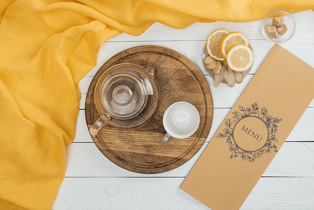 木制切割板和木制桌上菜单上的玻璃茶壶和空杯图片