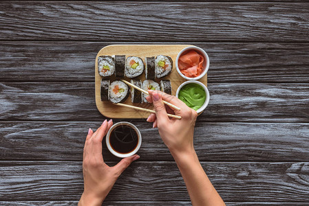 在吃寿司时拿着筷子和碗加酱油的人图片