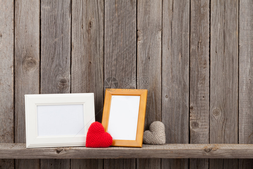 木墙前架子上的空白相框和心形礼物图片