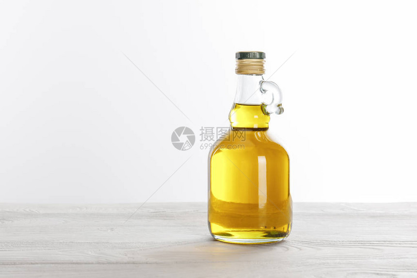 白色木制桌上的透明玻璃瓶油图片