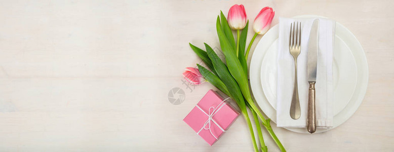 情人日餐桌设置粉红色郁金花和白木背景的礼品盒顶端视图横图片