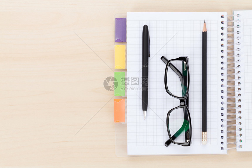 带有注纸笔和铅笔上的眼镜的办公桌顶面视图图片