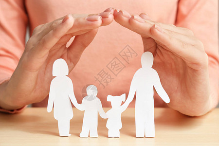女人用手遮住家庭的纸剪影特写保险概念图片