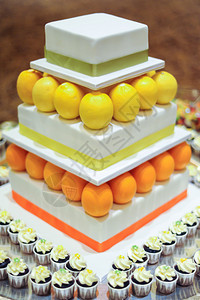 橙色柠檬3层白色婚礼蛋糕配迷你纸杯蛋糕图片