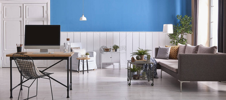 现代白色和蓝色墙壁背景木制工作台灰色沙发电脑和蓝色扶手椅白图片