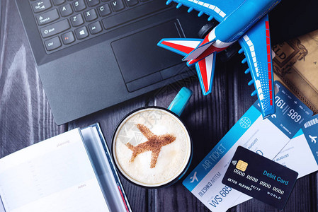 手持笔记本电脑飞机票咖啡卡布奇诺和信用卡都摆在桌面背景图片