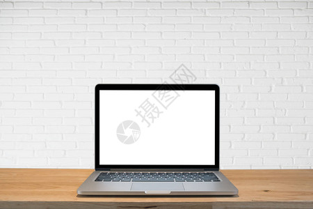 白色砖墙背景的笔记本电脑在木制桌子图片
