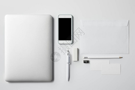 用智能手机和办公室用品在白色顶端的笔记本最顶图片