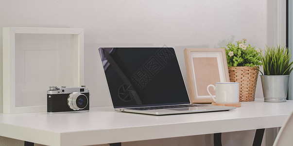 拥有开放空白屏幕笔记本电脑旧相机和白色木制桌上办公用品的舒适图片